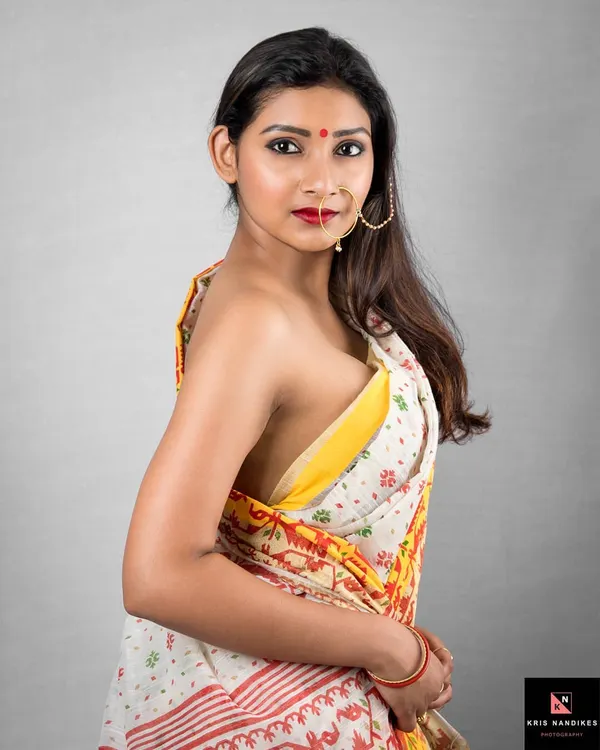 A classic Bengali saree look, captured with a direct and expressive gaze. The focus here is on the subtle power and beauty of traditional attire, highlighting the intricate details of the fabric and the model's confidence.