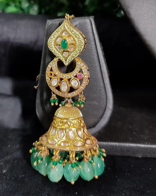 A magnificent pair of chandbali jhumkas with green enamel work and cascading green beads. These rental earrings are perfect for making a grand statement.
