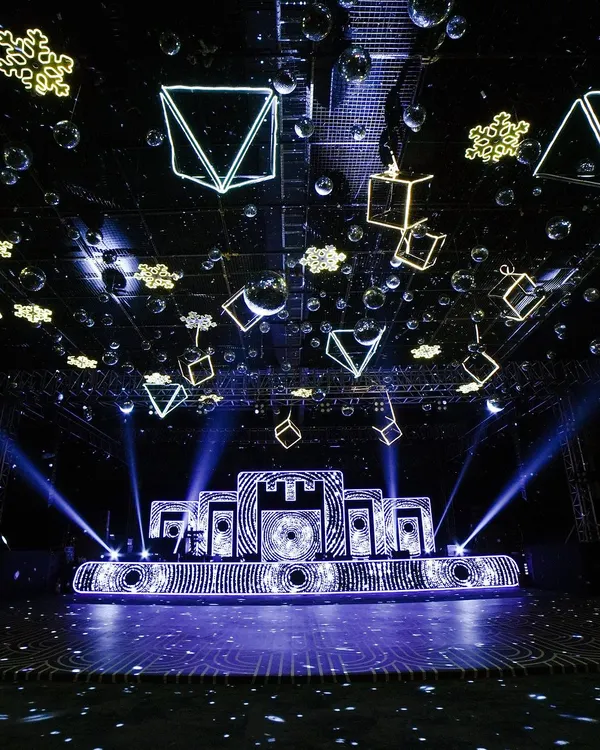 A glimpse into a Sangeet night designed to feel like a blockbuster awards show. The stage features a complex backdrop of geometric patterns and is complemented by dozens of suspended, illuminated cubes and disco balls, creating a truly immersive, high-energy atmosphere for performances.