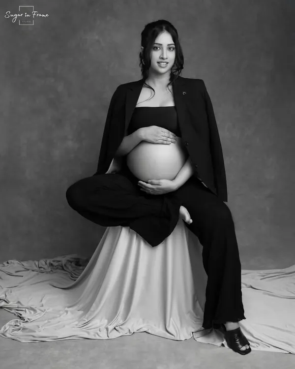 A powerful and confident solo maternity pose. The mom-to-be's seated pose, combined with the chic blazer and black and white finish, creates a modern and artistic portrait.
