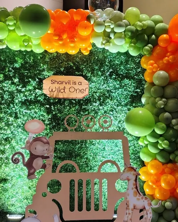 A closer look at our "Wild One" jungle safari theme. This setup features a lush greenery wall backdrop, a custom jeep cutout for photos, and an organic balloon garland in jungle-inspired shades of green and orange, perfect for a first birthday.