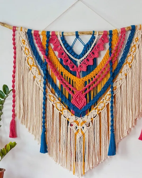 This is my "DAHILA" wall hanging, a large and vibrant statement piece designed to bring color and life to any room. It's made with layers of intricate knots and soft cotton cord on natural driftwood, perfect for a living room or even as a unique wedding backdrop.