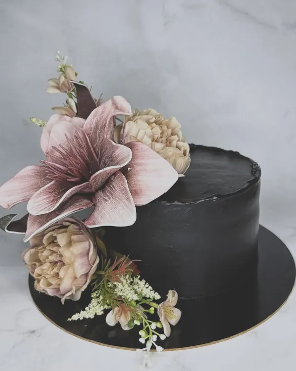 Guldasta or cake? This elegant black cake is adorned with a beautiful arrangement of wafer paper flowers, creating a dramatic and sophisticated look.