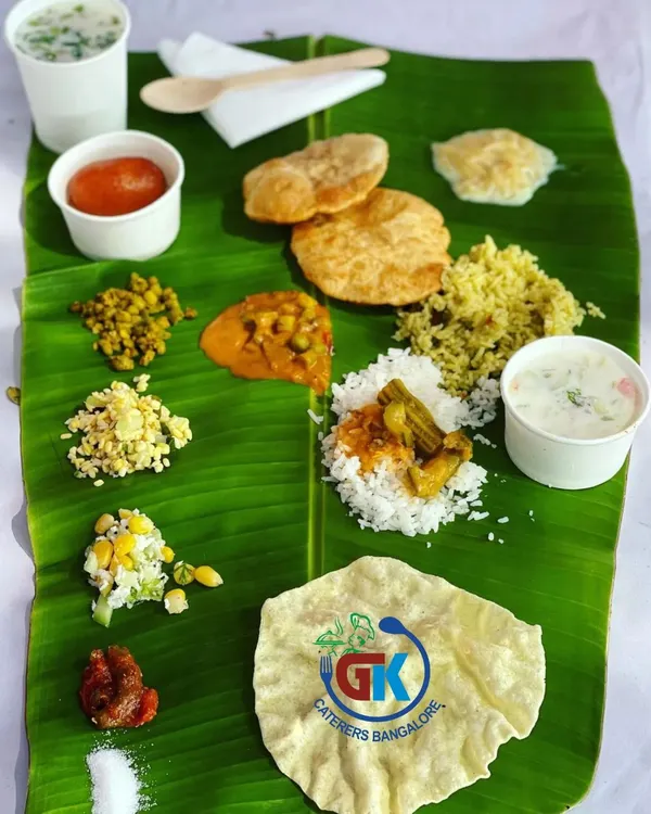 A Complete Vegetarian Meal: A perfectly balanced South Indian meal served on a banana leaf. It includes rice, sambar, poori, kosambari, palya, pickle, sweet pongal, and a gulab jamun.
