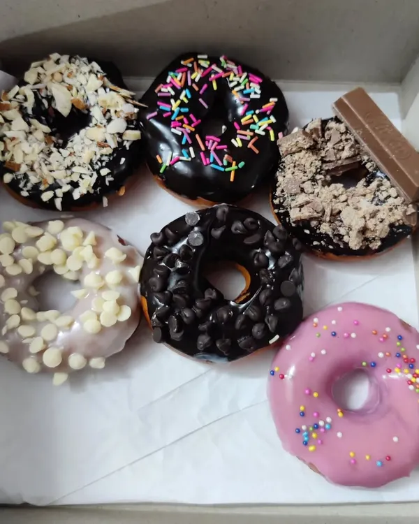 This assorted box of donuts is one of my most popular gift items. It features a mix of glazes like rich chocolate, sweet strawberry, and creamy white chocolate, with toppings ranging from rainbow sprinkles and chocolate chips to crushed KitKat and crunchy almonds.