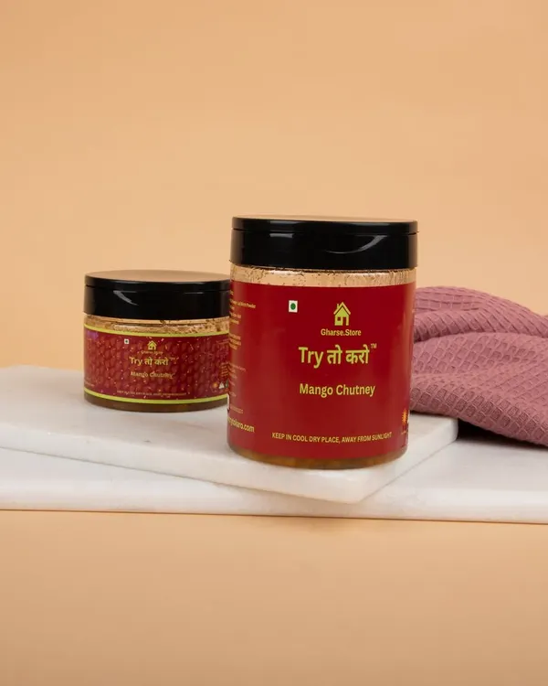 Two jars of Mango Chutney styled on a white marble slab with a pink cloth, creating a clean and appetizing look.