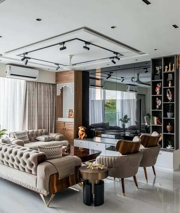 This is the feeling of home we strive to create. This living room in Mumbai combines luxurious comfort with a spacious, open layout, featuring a tufted sofa, modern track lighting, and a mirrored wall that enhances the sense of space.