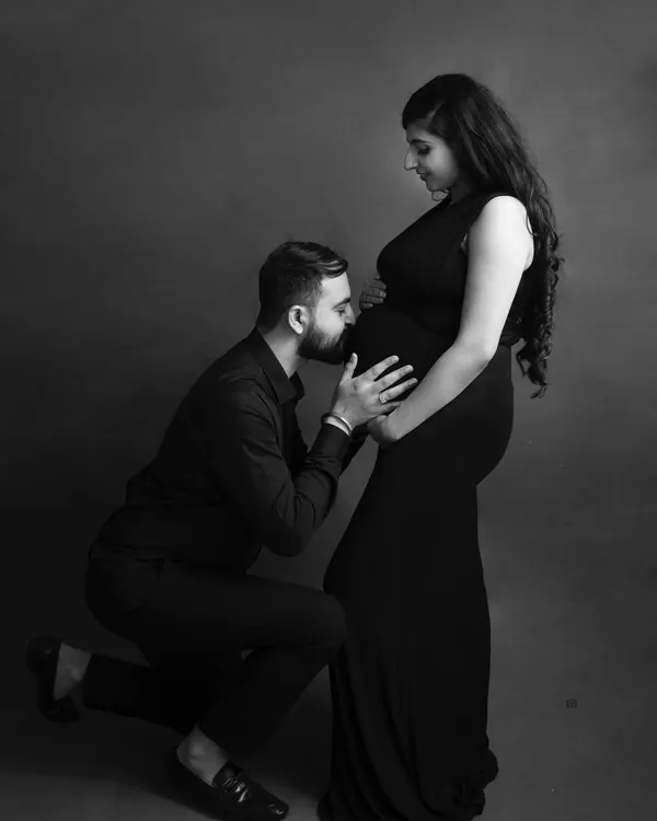 A classic and intimate black and white portrait of a partner kissing the baby bump. This pose is a timeless expression of love and anticipation.