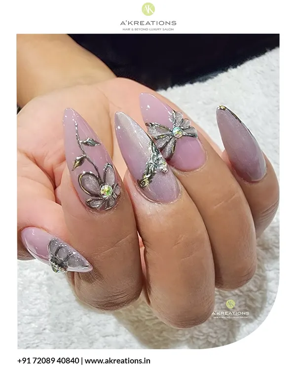 A detailed shot of the 3D floral and bow embellishments. These sculpted silver elements are placed on long stiletto nails to create a luxurious, multi-dimensional effect.