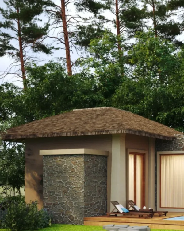 The exterior of a private cottage at Dev Villas, Kanha. The design uses a combination of local stone and a traditional pitched roof made from sustainable materials to integrate the structure into its forest setting.