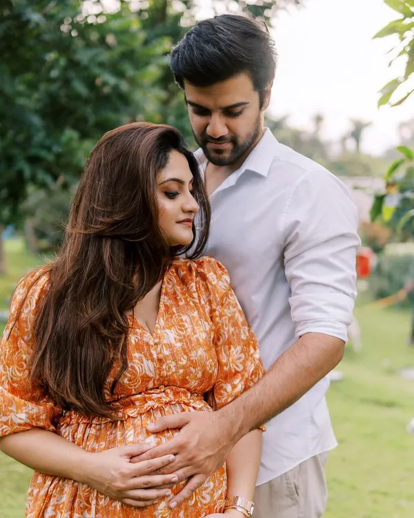 A classic and romantic outdoor maternity portrait. The way he holds her from behind in this beautiful green space feels both protective and loving, a perfect representation of their partnership.