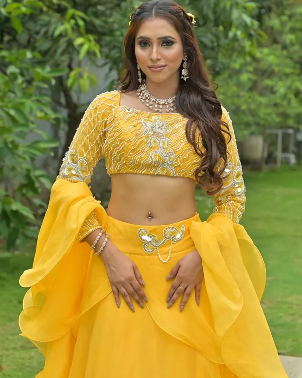 A vibrant yellow lehenga with flared sleeves, perfect for a Haldi or Mehendi ceremony. The look is completed with a delicate diamond necklace and matching earrings.