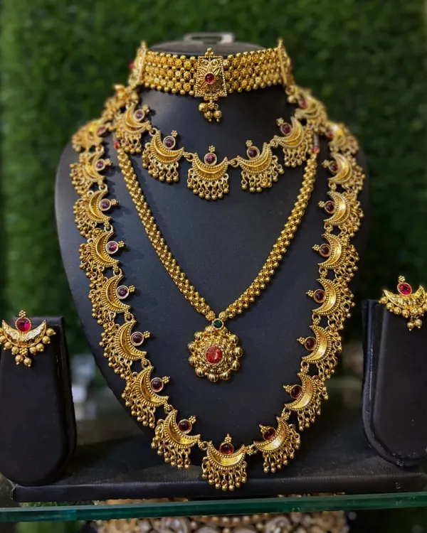 A classic temple jewellery set with a crescent motif, featuring a choker, a long necklace, and matching earrings.