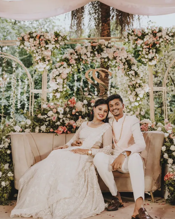 A beautiful portrait of the newly engaged couple, seated against a stunning floral arch at their Roka ceremony.