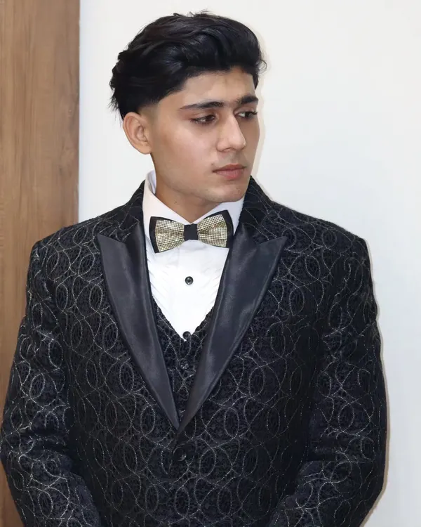 A closer look at a custom-designed three-piece tuxedo. The jacket features a subtle, intricate pattern, paired with a classic waistcoat and a sparkling bow tie for a touch of modern elegance.