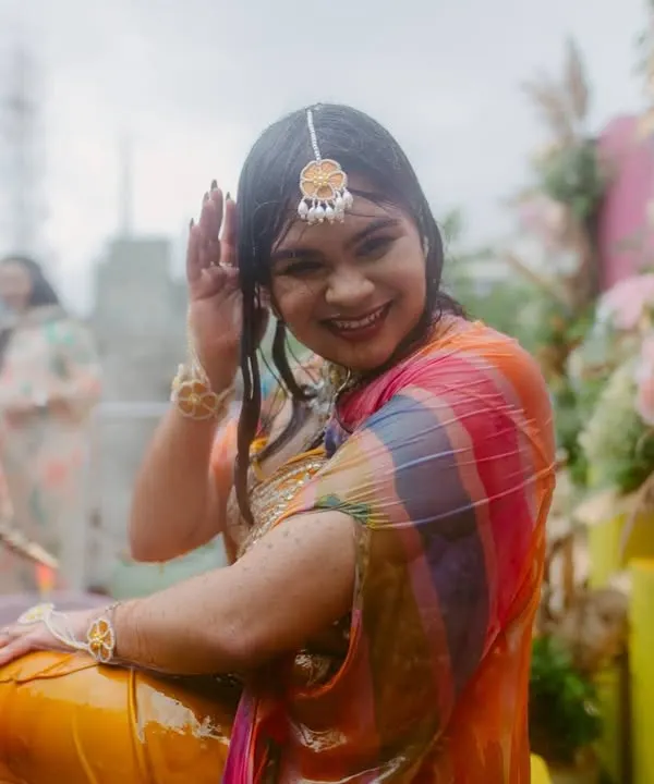 The pure fun of a Haldi ceremony. This bride is all smiles as she gets drenched in water, her colorful saree adding to the festive mood.