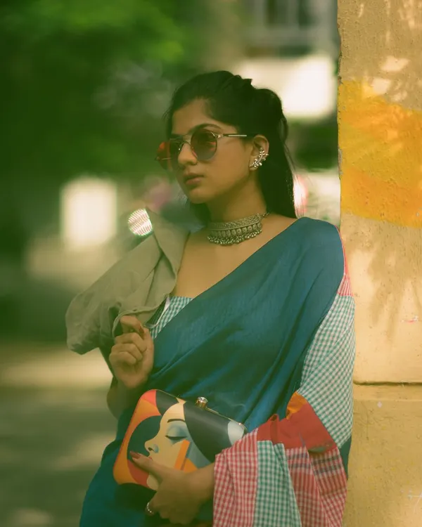 An edgy, modern look featuring a multi-colored patchwork saree. Paired with sunglasses and a quirky clutch, this shot against a graffiti wall shows a different side of saree styling.