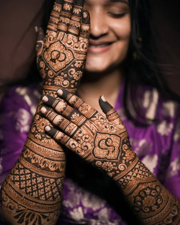 A classic engagement mehndi, beautifully captured to highlight the intricate details. The design features the couple's initials and intertwined rings, symbolizing their union.