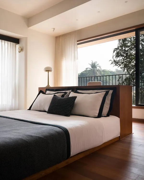 In the son's bedroom of our Multilevel House, the study table flows seamlessly into the platform bed. This integrated design keeps the room uncluttered and maximizes the connection to the two large windows and the nature beyond.