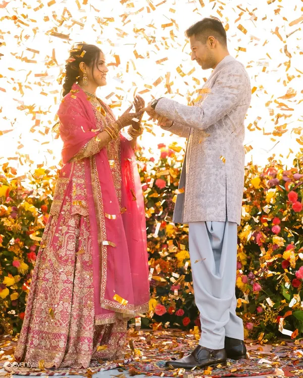 The moment of the ring exchange, showered in golden confetti and sunlight. This is pure joy and celebration, a perfect capture of their engagement.
