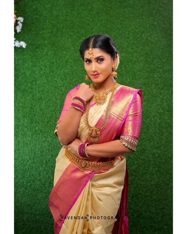 A classic South Indian look featuring a cream and pink silk saree. The makeup includes a warm, blended eyeshadow, defined brows, and a soft lip color to create an elegant and graceful appearance.