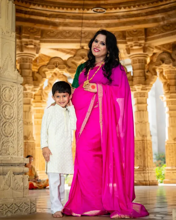 A beautiful portrait of a mother and son at a temple. The mom-to-be's vibrant pink saree and traditional jewelry celebrate her culture and her pregnancy.