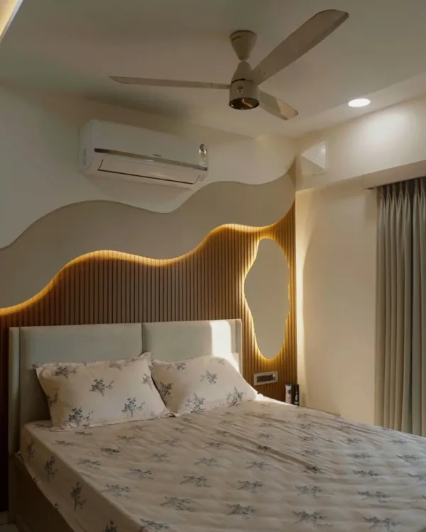 A master bedroom where organic, flowing lines on the wall create a sense of calm. The backlighting and fluted wood paneling add warmth and texture, making this a truly serene retreat.