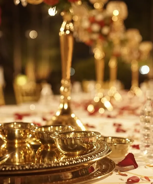 The details matter. This close-up shows the elegant brass thali and bowls I use for my Royal Thali service, set on a beautifully decorated table with flower petals.