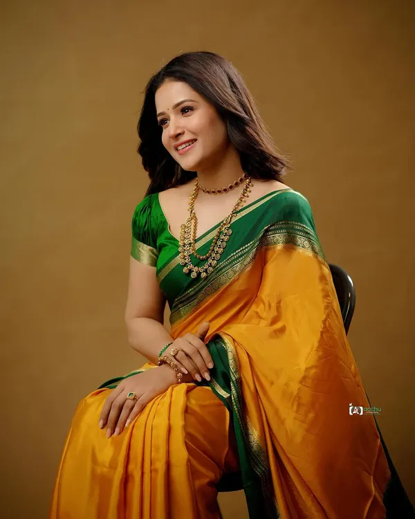 A classic studio portrait that celebrates the beauty of traditional attire. The rich yellow and green silk saree, paired with antique gold jewelry, creates a timeless and graceful look.