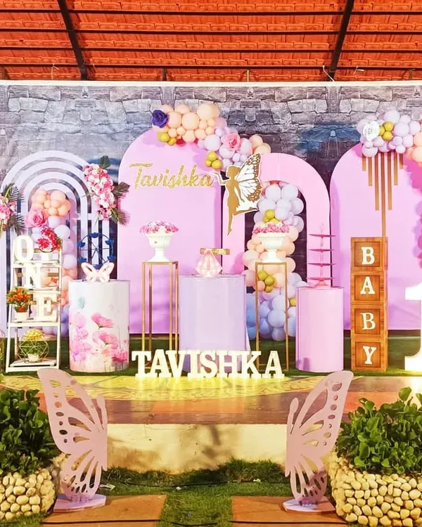 This grand butterfly-themed first birthday is a perfect example of how I transform a space into a magical wonderland. The setup features large-scale butterfly wing cutouts, a personalized backdrop with the name 'Tavishka', custom-wrapped pedestals for the cake, and a stunning pastel balloon garland, all creating a breathtaking photo opportunity.