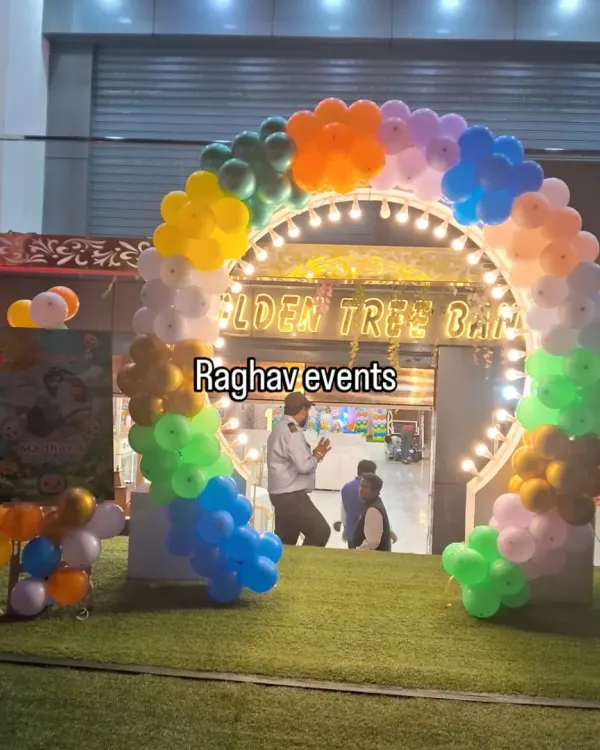 A vibrant, multi-colored balloon arch at the entrance of a banquet hall. This arch is lit up and creates a welcoming and festive atmosphere for guests as they arrive.
