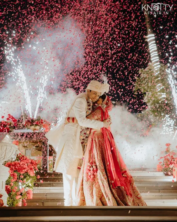 This is the moment every story builds towards. The couple's embrace under a sky bursting with fireworks and confetti captures the pure, explosive joy of their union. It's a grand, cinematic memory from their beautiful wedding day.