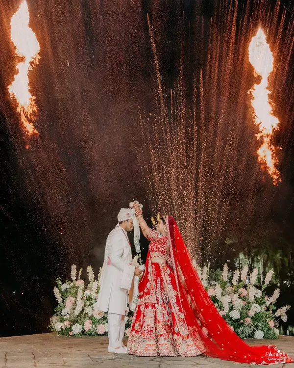 A spectacular varmala moment for Sakshi and Ayush, framed by dramatic fire pyrotechnics. We excel at capturing these peak moments with precision and artistry.