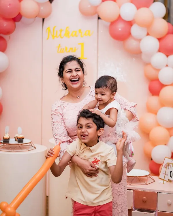 A mother's joyful laugh with her two children during a first birthday party. We capture the real, chaotic, and beautiful moments that define family celebrations.
