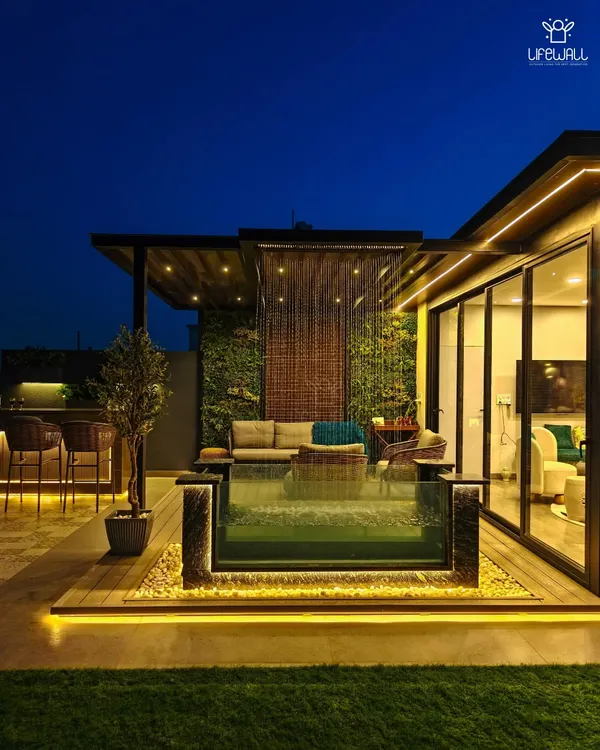This is what I mean by a private villa vibe. This rooftop features a custom glass-walled pool with a rain shower, a fully equipped bar, and a cozy lounge area under a pergola, all brought to life with ambient lighting for the perfect evening escape.