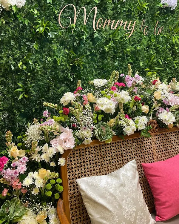 For this botanical garden baby shower, we created a lush greenery wall with a 'Mommy to be' sign. The seating area is adorned with an abundance of fresh, colorful flowers for a luxurious and natural feel.