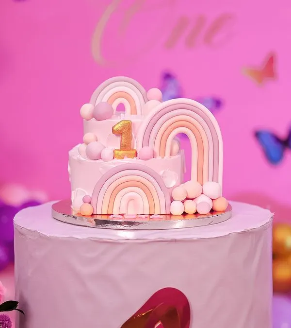 A beautiful two-tiered cake for a first birthday, decorated with pastel rainbows and delicate butterflies. This cake was the centerpiece of a whimsical and elegant celebration.