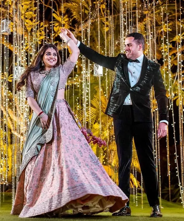 A perfect twirl against a backdrop of cascading fairy lights. This shot captures the bride's joy and the beautiful movement of her lehenga during a sangeet night performance.