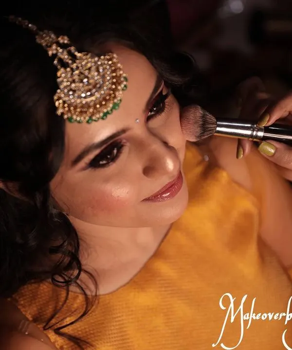 The process of creating a flawless base. Here, I am applying blush to add a natural flush of color to the cheeks for Chinmayi's mehendi look.