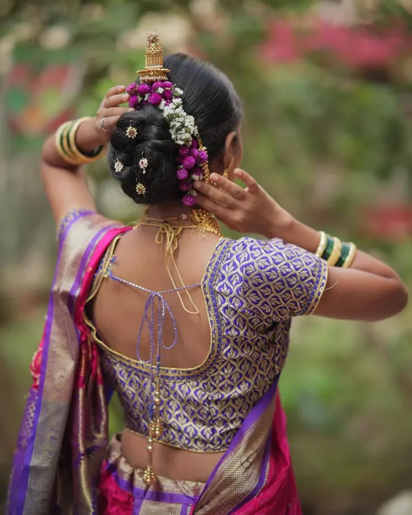 A classic Maharashtrian 'khopa' or bun hairstyle, beautifully decorated with fresh flowers and a traditional hair accessory. This is a popular choice for Nauvari sarees.