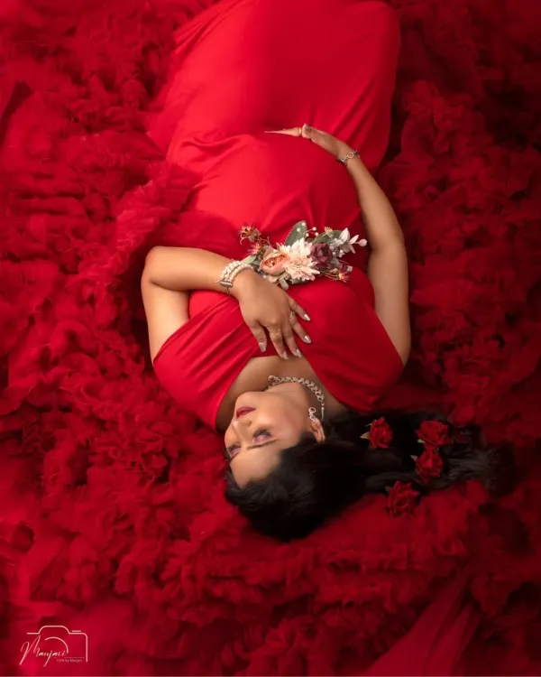 A moment of serene beauty. This mama-to-be is a vision in red, captured in our artistic 'Sleeping Pose' setup, creating a powerful and timeless portrait of motherhood.