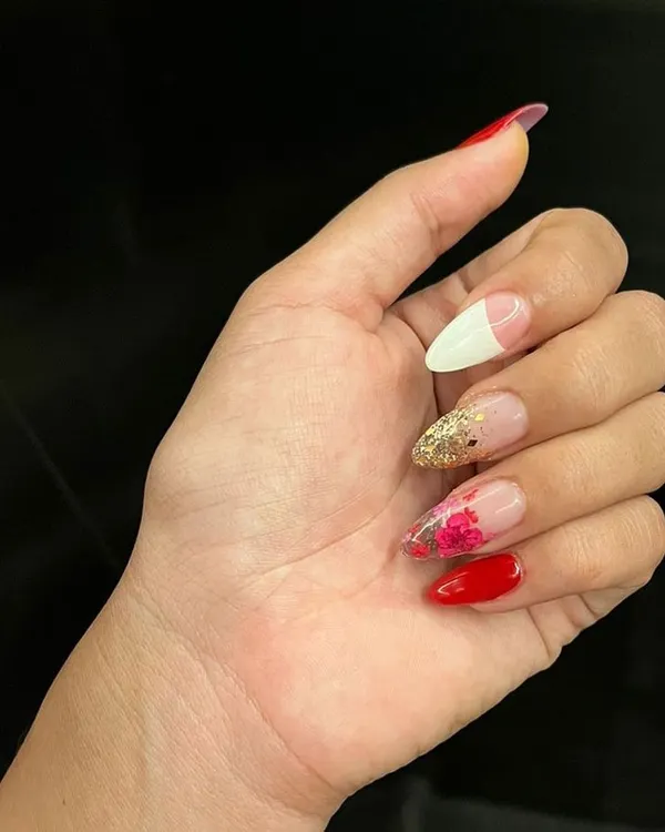 An example of our creative nail artistry, combining a French tip, glitter, delicate floral painting, and a bold solid red. This set shows the range of techniques our artists can use in a single, cohesive design.