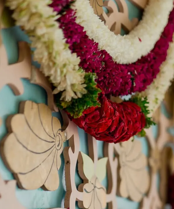 A close-up of a custom-carved backdrop with a traditional floral garland. This highlights our team's skill in creating bespoke decor elements.