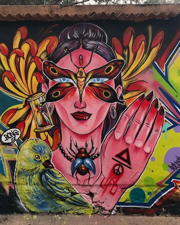 A detailed view of the figurative portion of a mural. This character features a butterfly mask and is surrounded by symbolic elements like an hourglass, showcasing a more illustrative and mystical side of my spray paint art.
