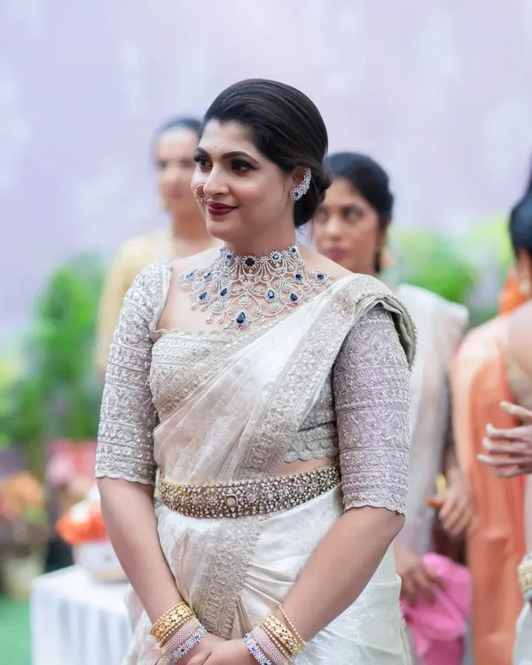 A beautiful and elegant look for a wedding guest. The makeup is sophisticated, with a bold lip and defined eyes that complement her stunning white and silver saree.