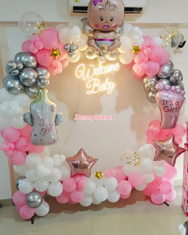 A perfect circle of joy to welcome a new baby. This beautiful balloon ring in pink, white, and silver, complete with a "Welcome Baby" neon sign, creates a stunning centerpiece for a homecoming celebration.