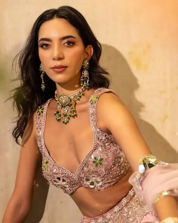 A beautiful shot from a campaign for Surabhi Chopra Label. The model wears a delicate pink lehenga with mirror work, styled with a contrasting emerald necklace for a fresh, summery feel.