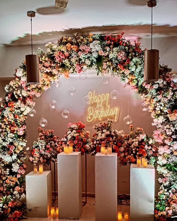 I created this luxurious birthday backdrop featuring a full arch of fresh, multi-colored flowers and a custom "Happy Birthday" neon sign. This elegant floral decoration is perfect for milestone birthdays or anniversary celebrations.