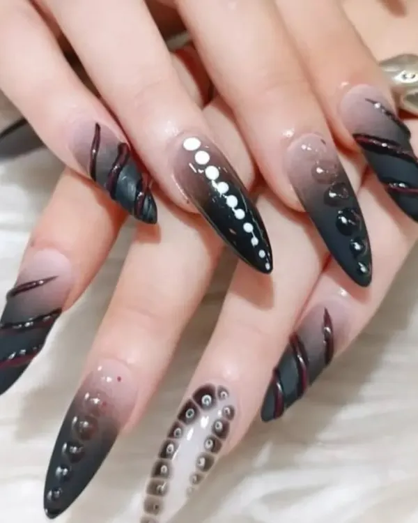 For those who love avant-garde designs, this set features extra-long stiletto nails with a black ombre base and intricate 3D textures and patterns.