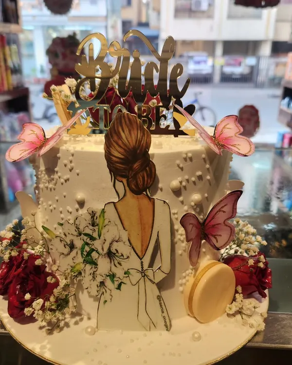 A beautiful and modern 'Bride to Be' cake. This design features an elegant illustration of a bride, delicate wafer paper butterflies, and fresh flowers.